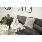 Canapé en velours gris foncé avec plaid en laine écrue à franges et motifs en relief