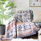 Plaid nordique coloré posé sur un canapé, avec des motifs géométriques et franges décoratives