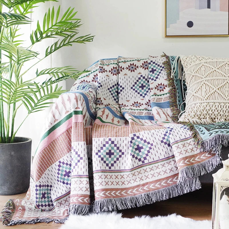 Plaid nordique coloré posé sur un canapé, avec des motifs géométriques et franges décoratives