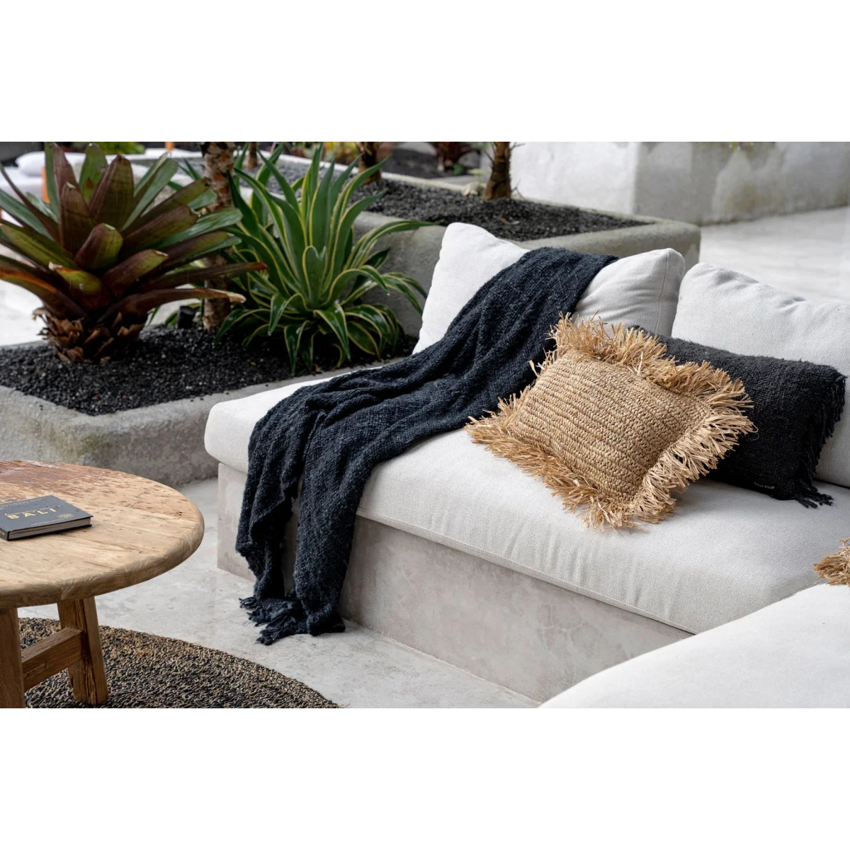Canapé d’extérieur blanc avec couverture bleue foncée et coussins en tissage noir