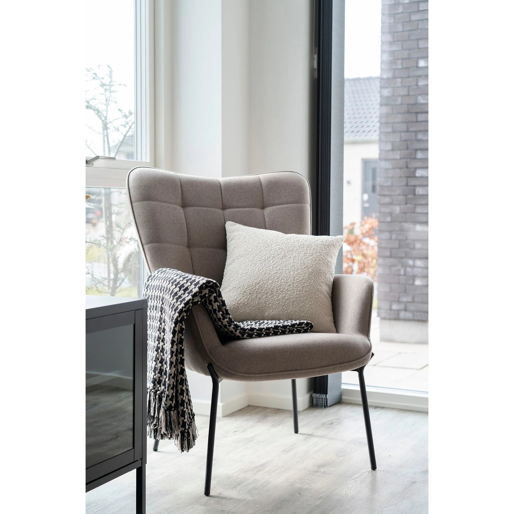 Fauteuil beige à piétement noir avec coussin texturé et plaid pied-de-poule noir et beige