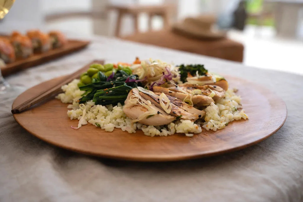 Assiette ronde en racine de teck avec riz légumes et poulet grillé