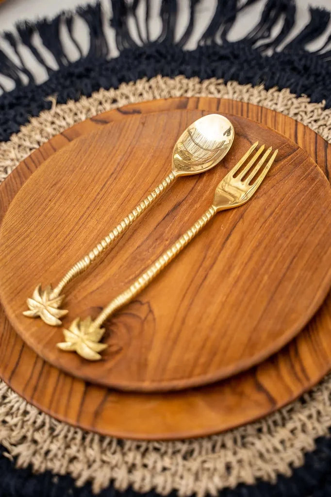 Cuillère et fourchette à poignée en palmier doré sur une assiette en teck