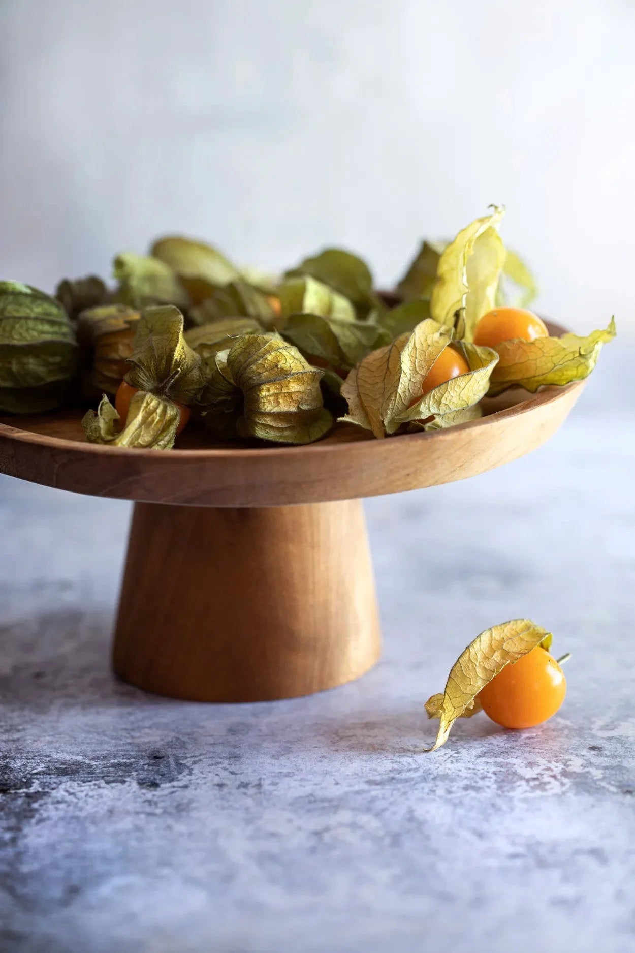 Plat à gâteau en teck naturel avec des groseilles dorées fraîches et un fruit sur le comptoir