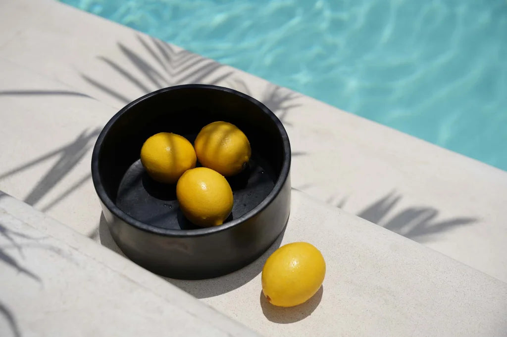 Lemons frais dans un bol noir du ensemble Le plat cylindrique brûlé noir