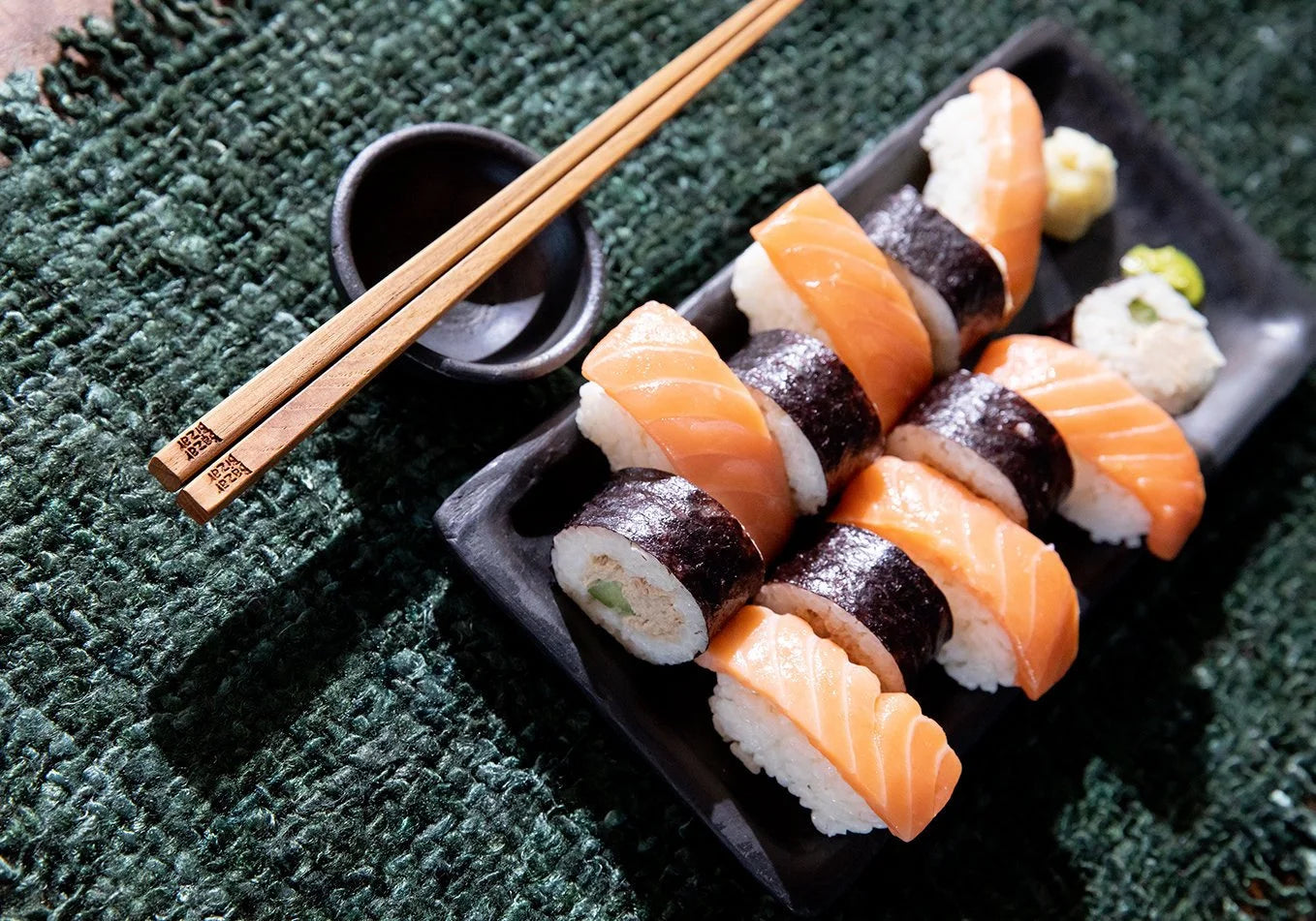 Assortiment de sushi avec des baguettes sur un plateau rectangulaire en terre cuite noire