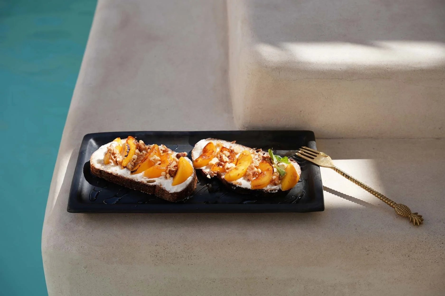 Deux tartines de pêche et fromage à la crème sur Plateau à sushi rectangulaire en terre cuite noire