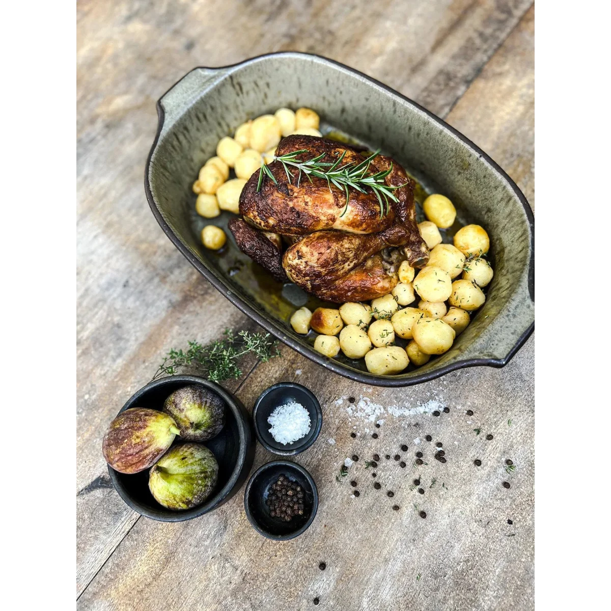 Poulet rôti avec pommes de terre et romarin dans un plateau en céramique vert grisâtre