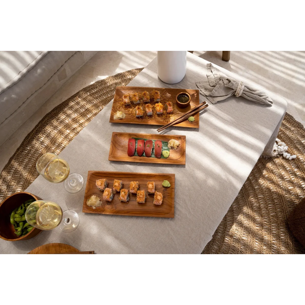 Plateau rectangulaire en racine de teck avec sushi, sashimi, edamame, et vin blanc