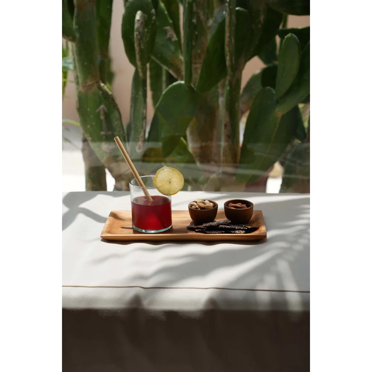 Verre de jus rouge avec tranche de citron, noix, fruits secs sur plateau en teck
