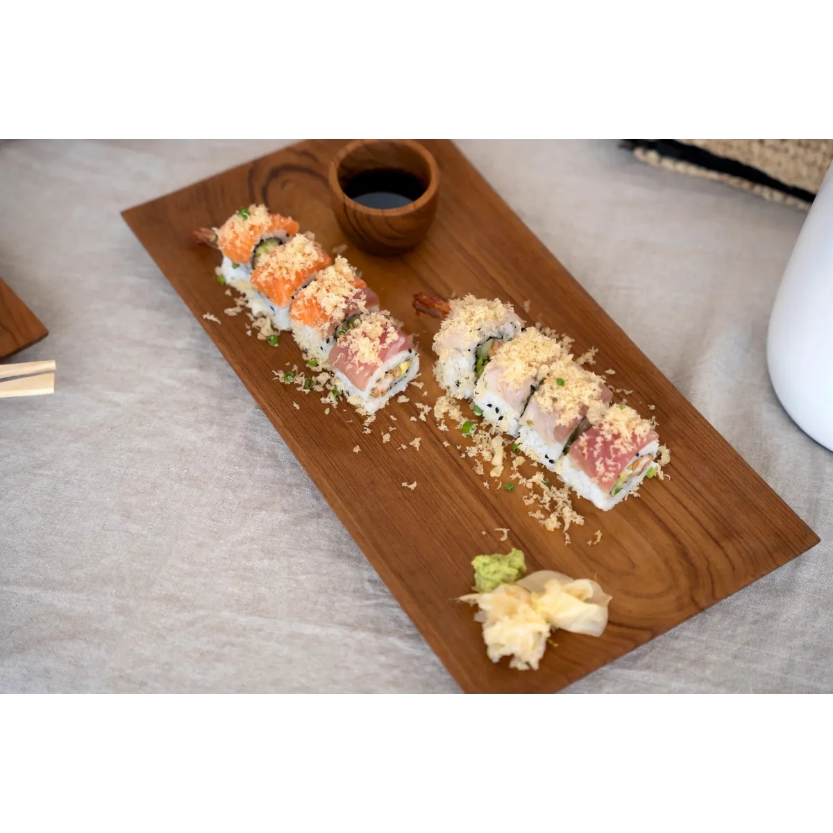 Assortiment de sushis avec tempura, wasabi, gingembre et sauce soja sur plateau en teck