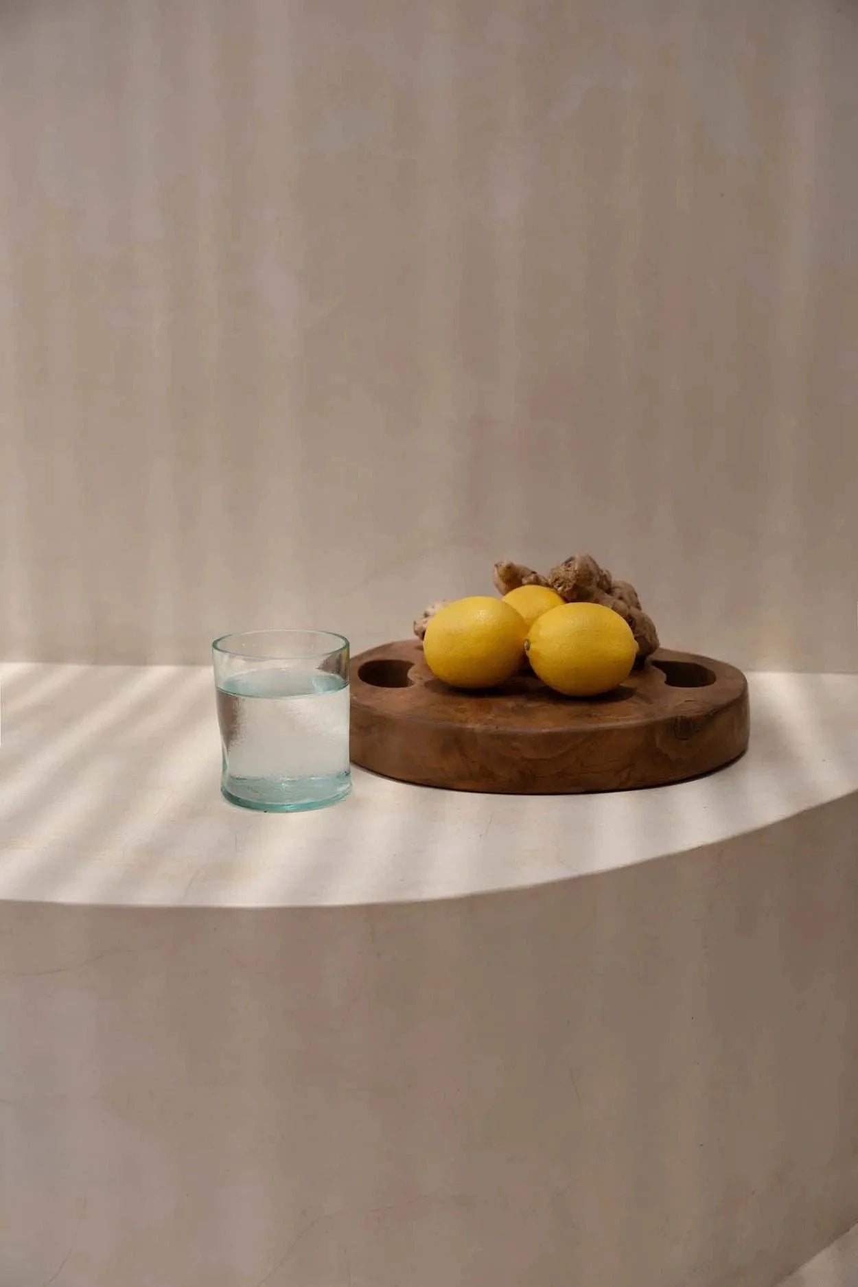 Lemons et gingembre sur un plateau en teck naturel avec verre d’eau, design élégant