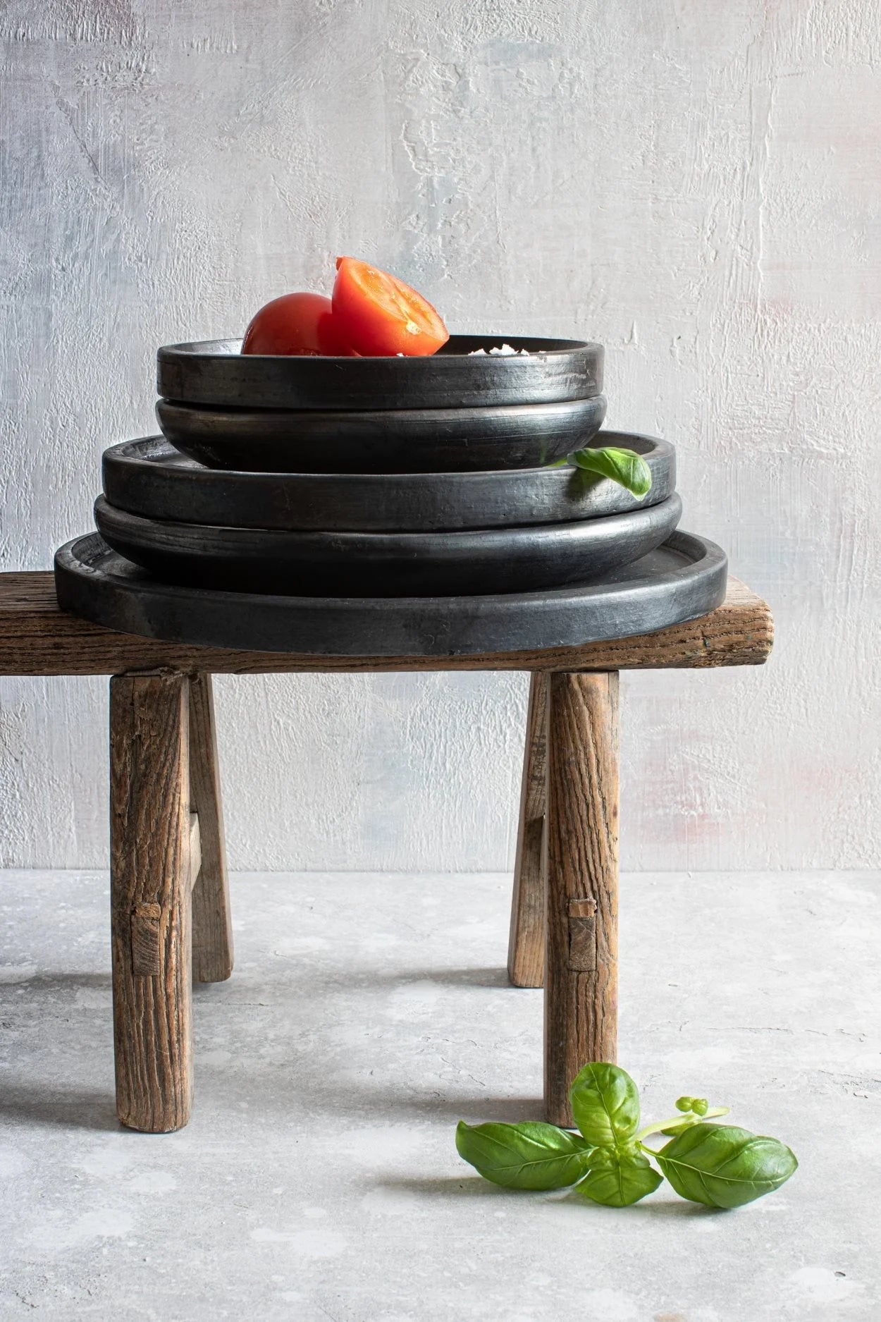 Plateau rond en terre cuite noire finition mate avec des assiettes en céramique noire empilées