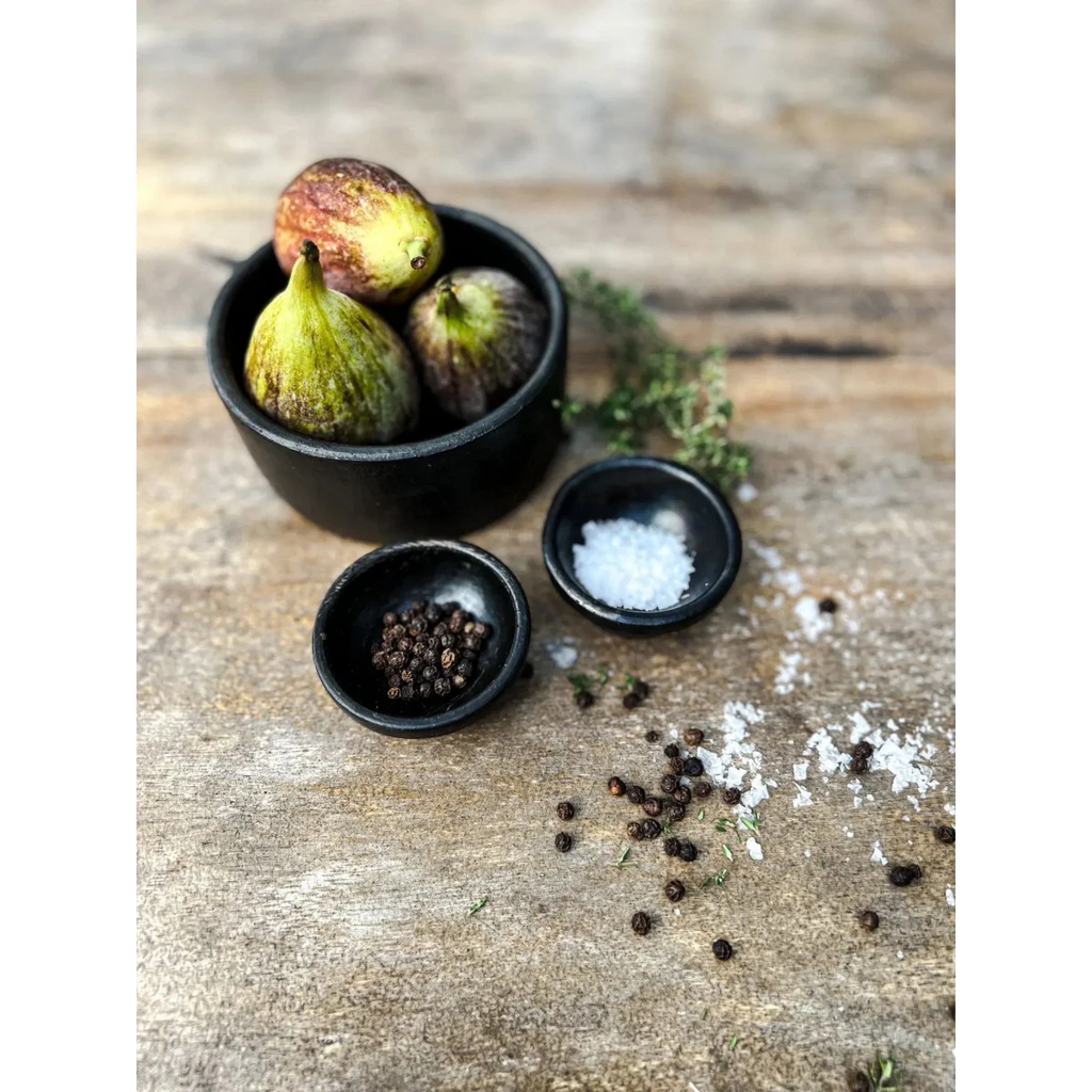 Figues mûres dans un bol noir avec poivre noir et sel marin en petits bols