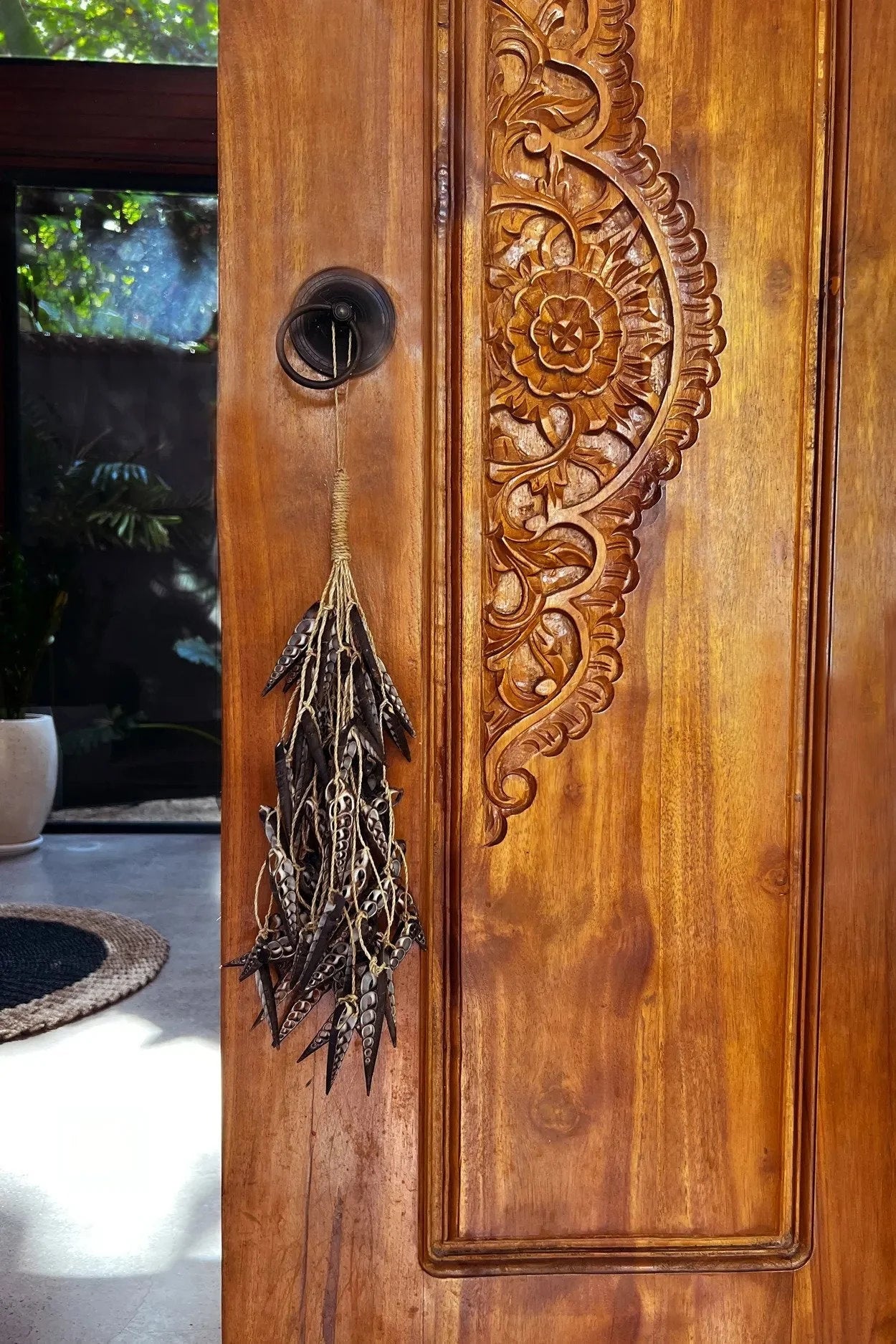 Porte en bois ornée de détails sculptés pour le produit Pompon en coquillages naturels marron