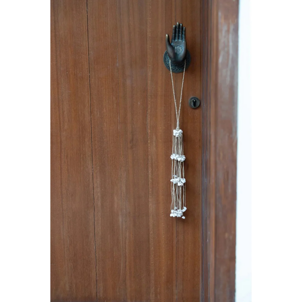 Pompon décoratif en coquillages blancs, cordes naturelles et heurtoir en bois en forme de main