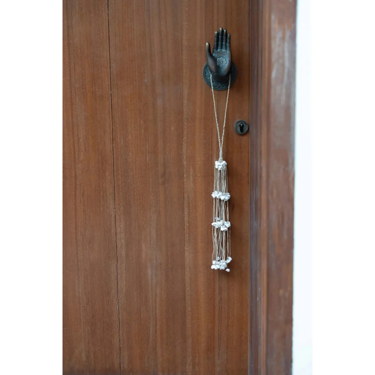 Pompon décoratif en coquillages blancs, cordes naturelles et heurtoir en bois en forme de main