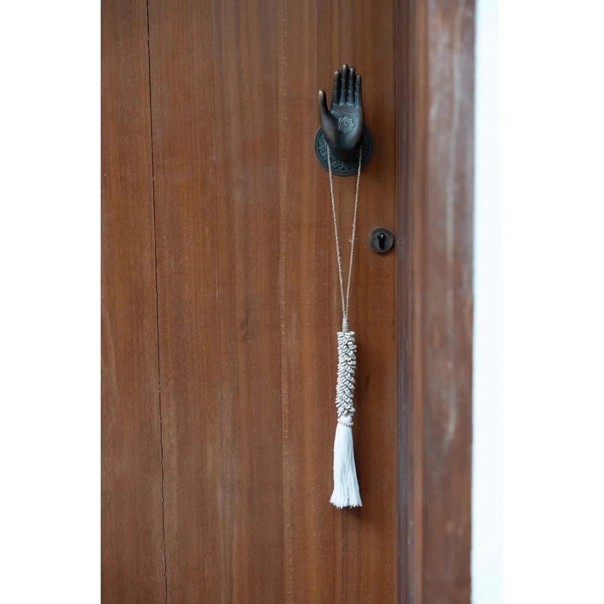 Heurtoir porte main en bois brun avec pompon et accents métalliques