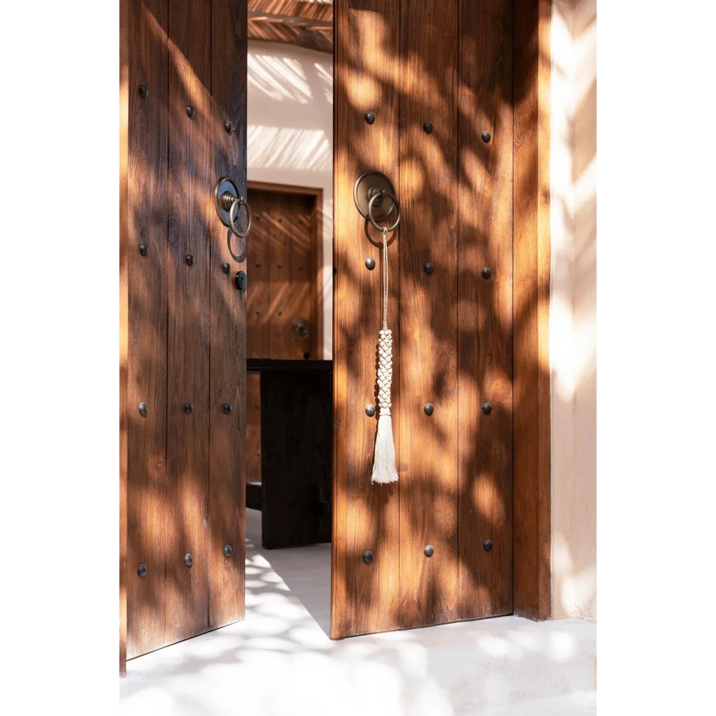 Porte en bois avec pênes circulaires en métal et pompon suspendu au bec-de-cane