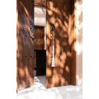 Porte en bois avec pênes circulaires en métal et pompon suspendu au bec-de-cane