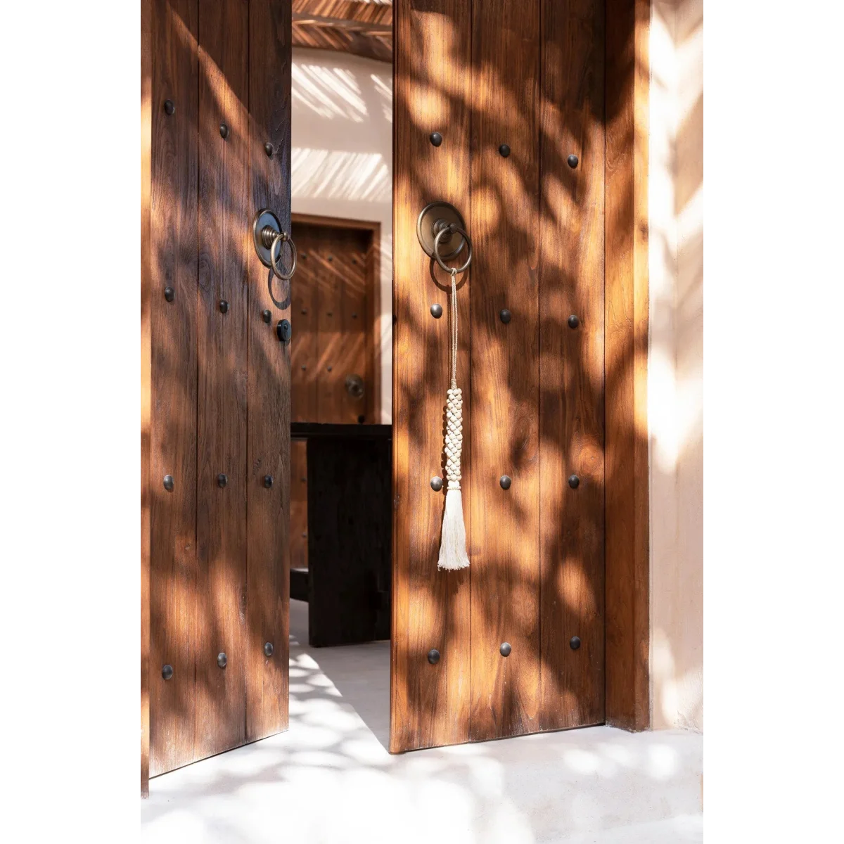 Porte en bois avec pênes circulaires en métal et pompon suspendu au bec-de-cane