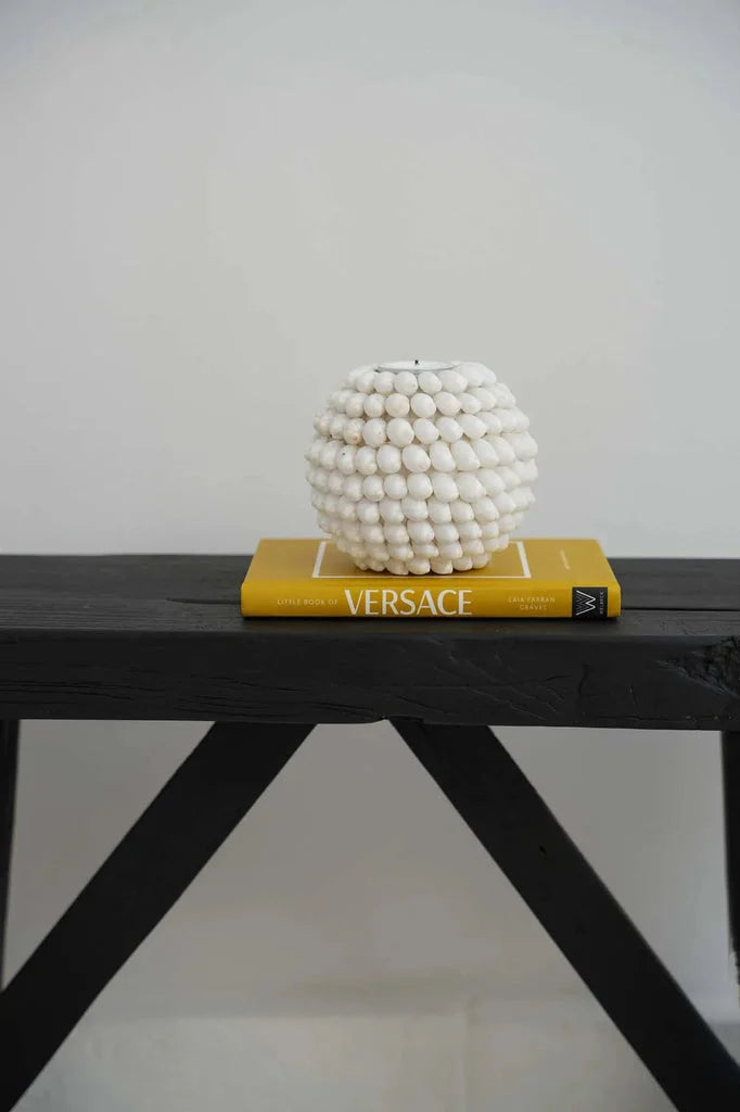 Vase sphérique blanc sur livre jaune dans Le porte-bougie à bulles M