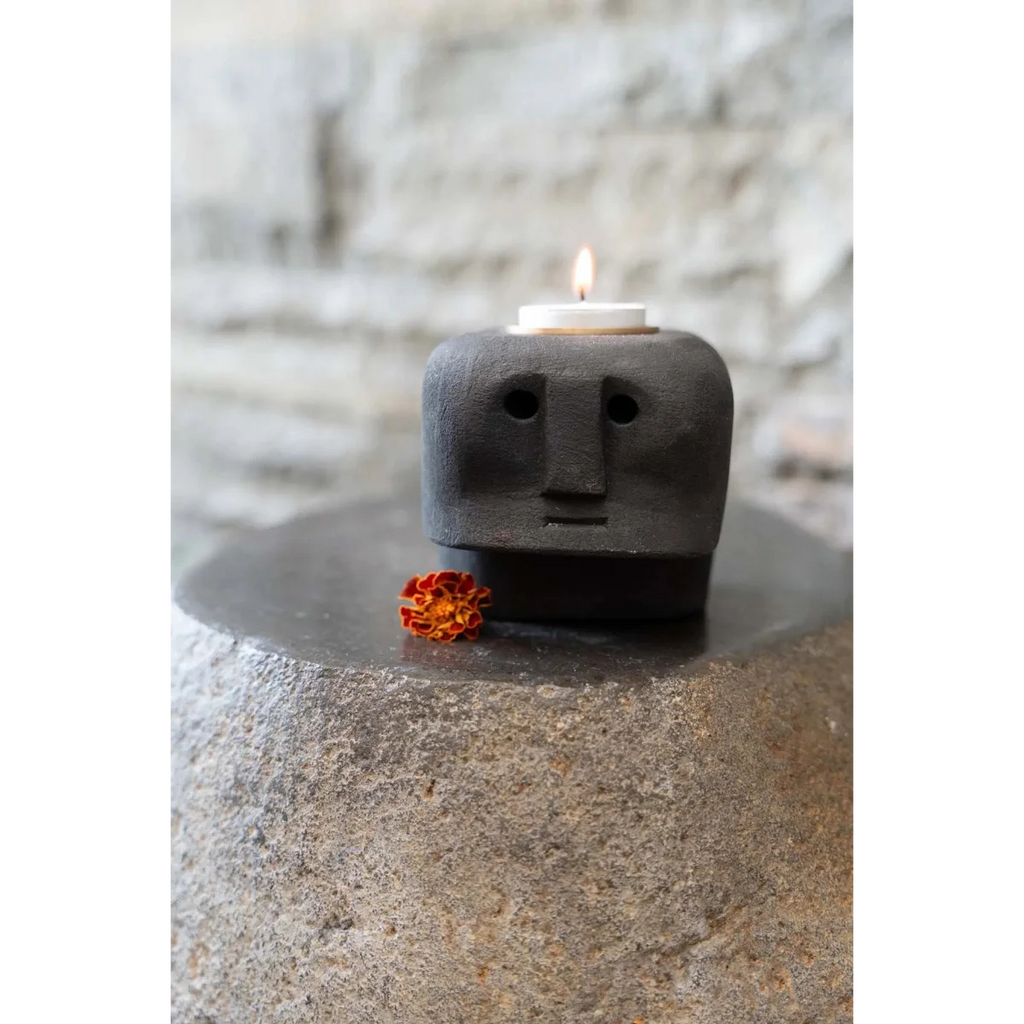 Porte-bougie en grès noir sculpté visage stylisé avec petite fleur orange à la base
