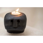 Bougeoir visage en grès noir sculpté avec bougie tea light allumée