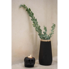 Vase noir en grès avec feuillage vert clair et bougeoir tête de mort allumé