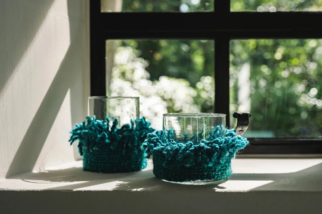 Deux mugs en verre avec des manchons en laine turquoise pour une ambiance cozy