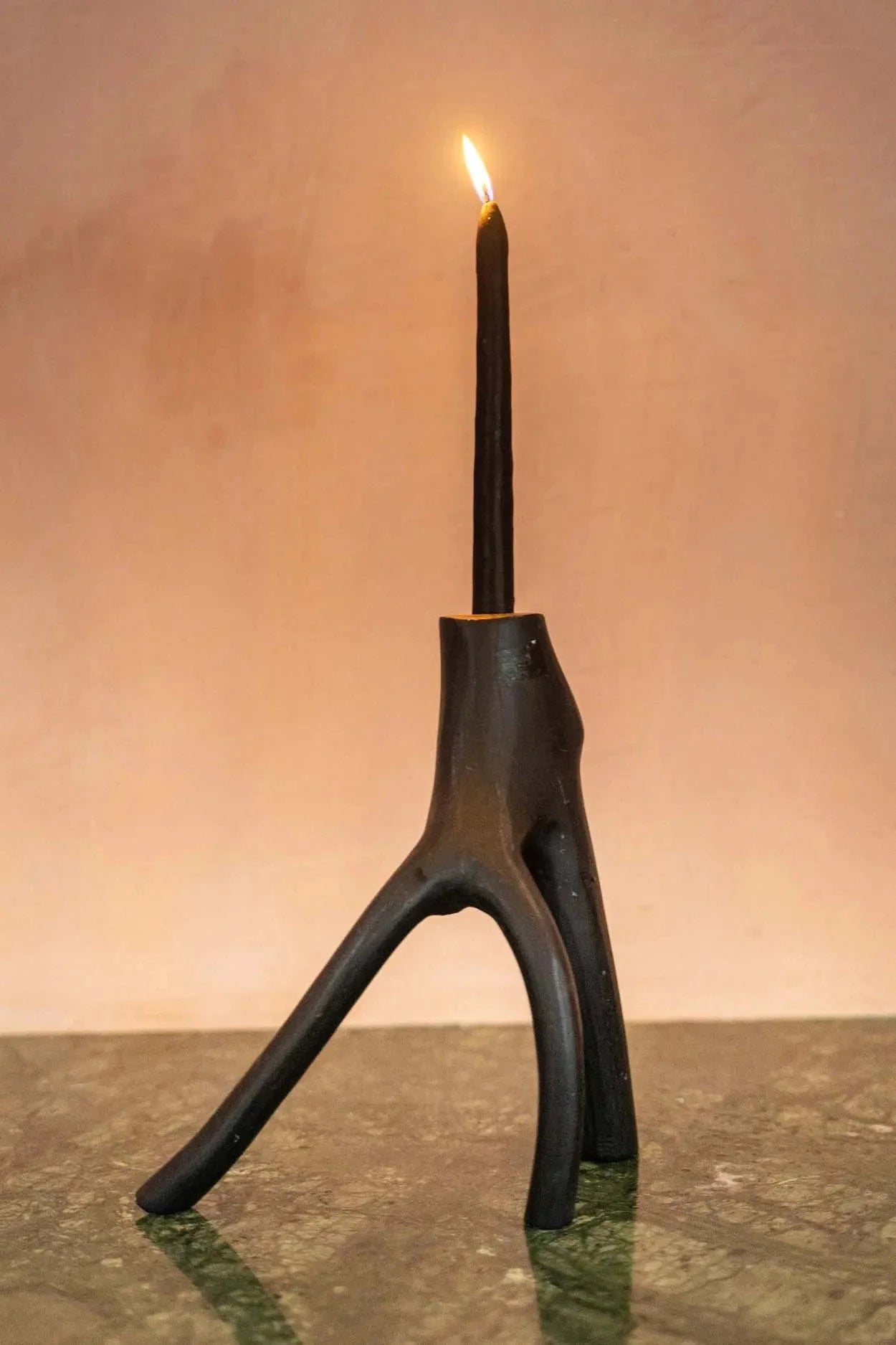 Bougie noire dans un porte-bougie sculptural en métal sombre au design naturel