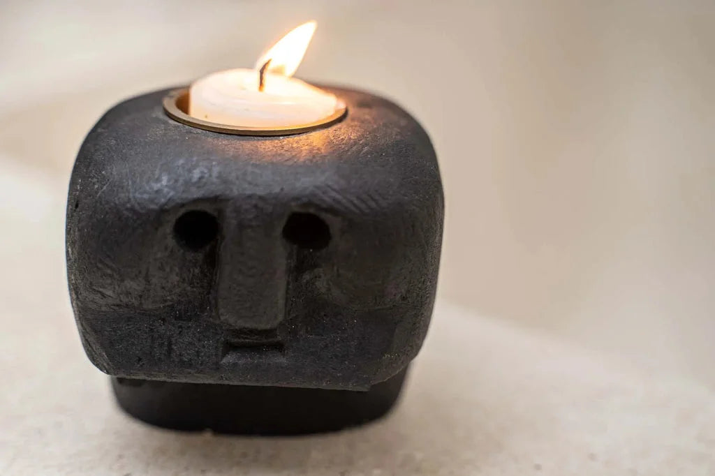Porte-bougie Sumba Stone n°27 en forme de tête noire avec bougie allumée