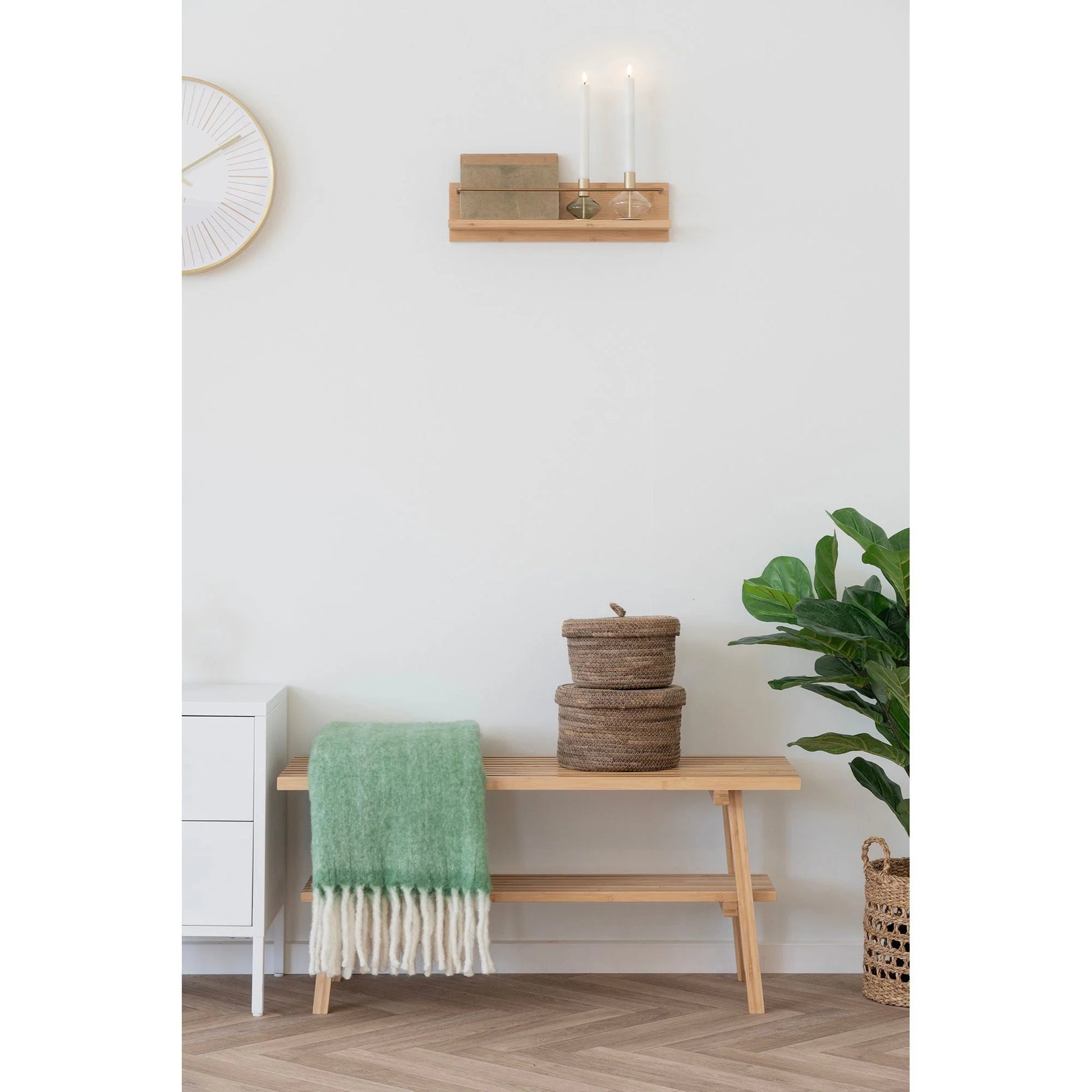 Banc en bois clair avec couverture verte et porte-bougie en verre et métal doré