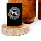 Carte de visite noire avec un motif de mandala blanc.