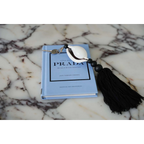 Porte-clés Prada coquillage cauri noir et blanc avec pompon en coton et cuillère blanche sur marbre