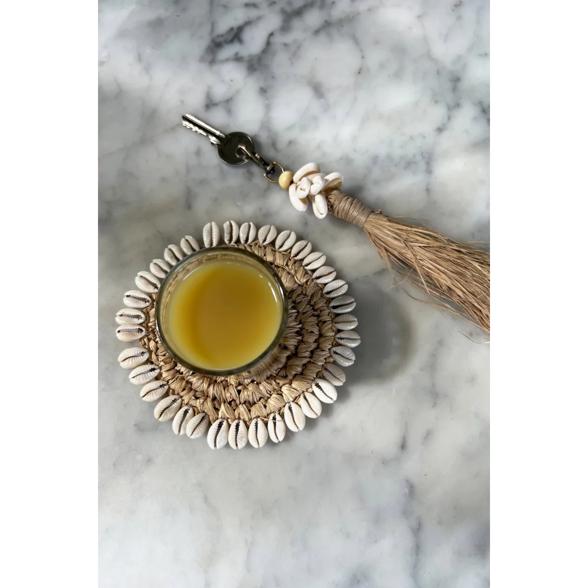 Porte-clés pompon en raphia avec coquillages blancs et liquide jaune
