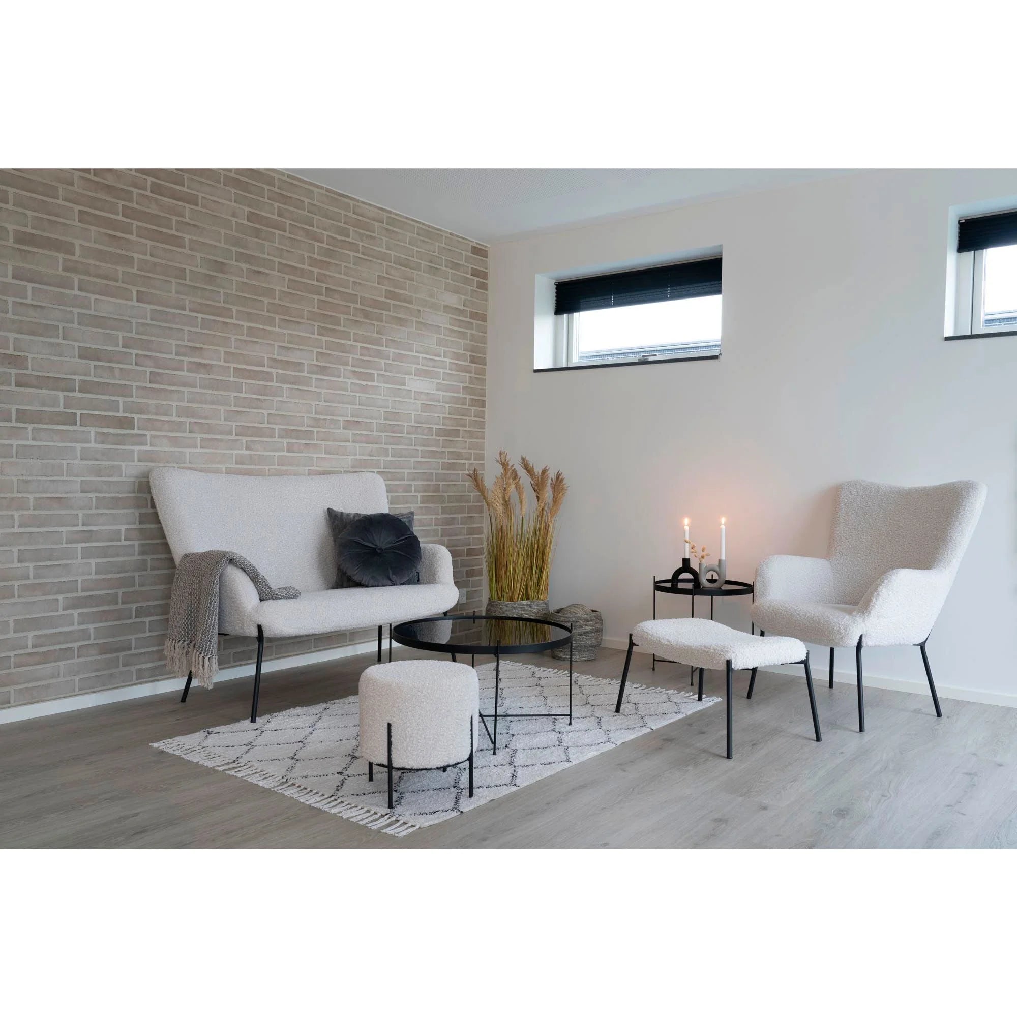 Canapé blanc capitonné pieds métal noir avec plaid gris sur accoudoir