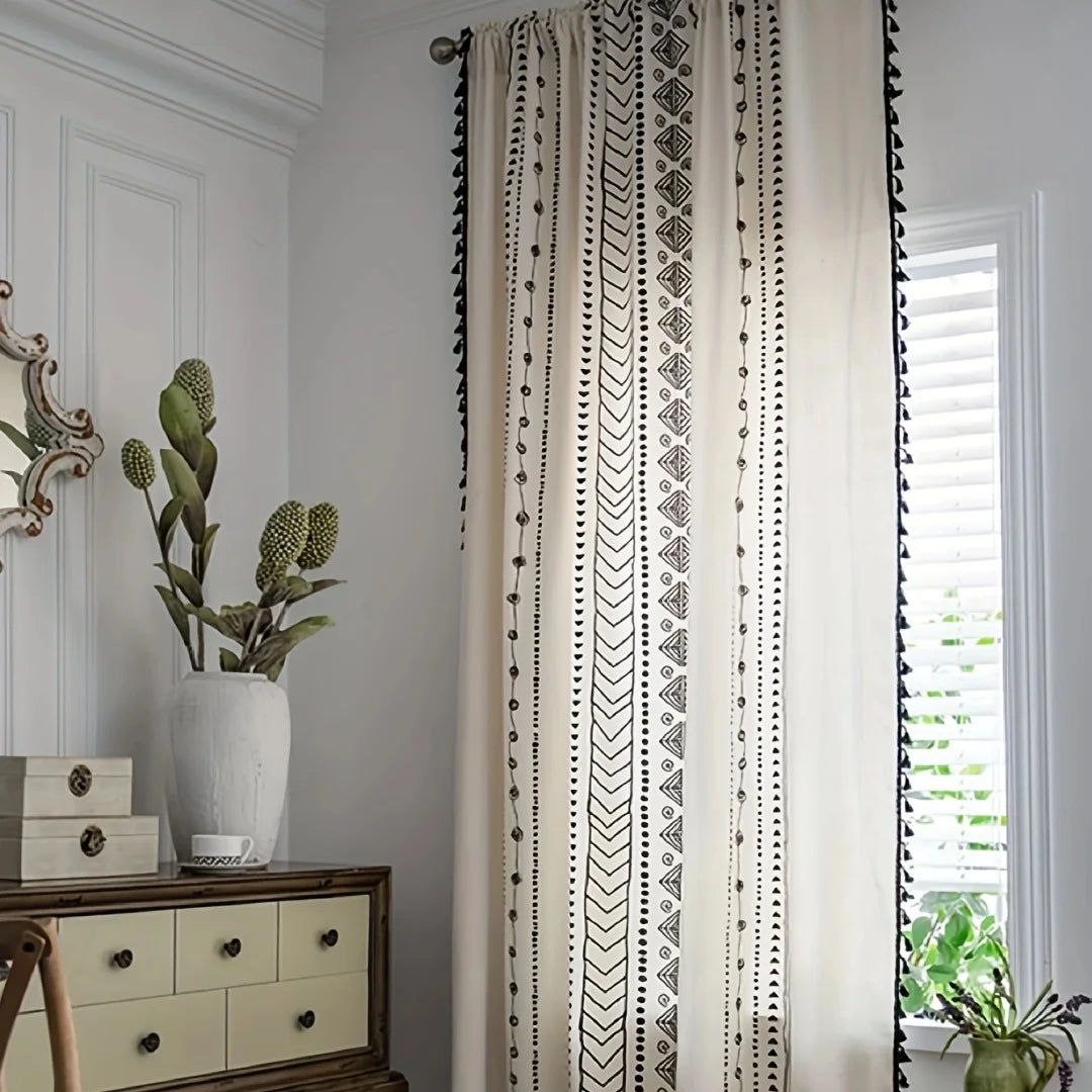 Rideau bohème à motifs géométriques noirs et blancs installé dans un salon.