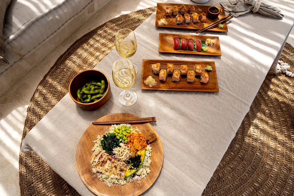 Assortiment de cuisine japonaise avec sushi, edamame, riz coloré et vin blanc dans un saladier en teck naturel