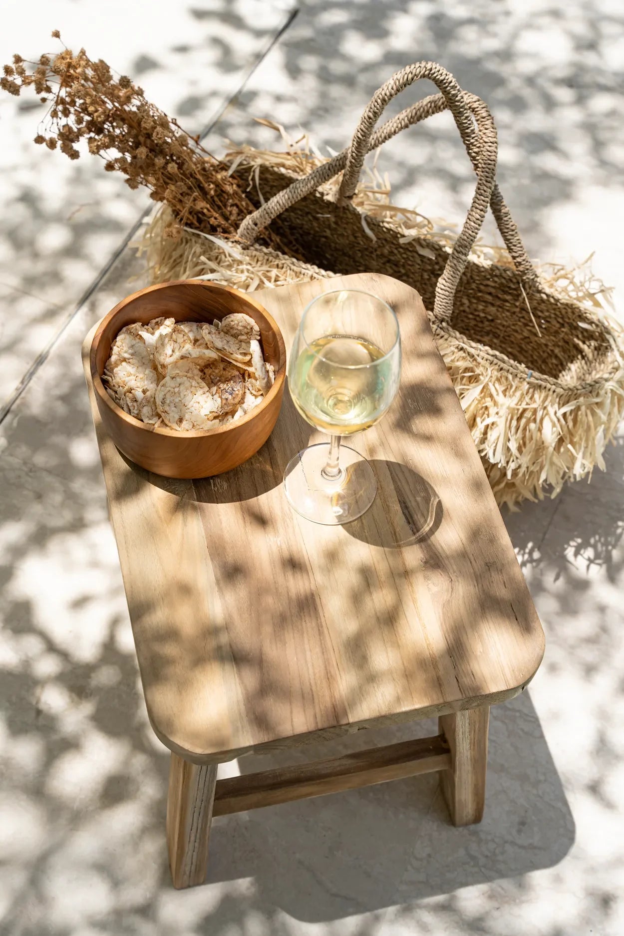 Tabouret en teck naturel avec verre de vin et snacks pour une décoration noble