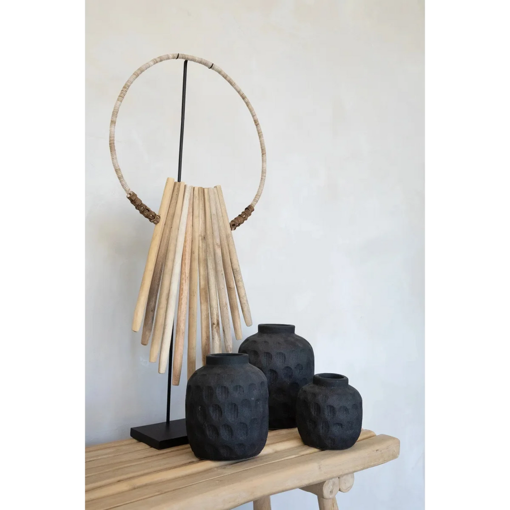 Art tribal décoratif avec trois vases noirs texturés sur socle en bois naturel