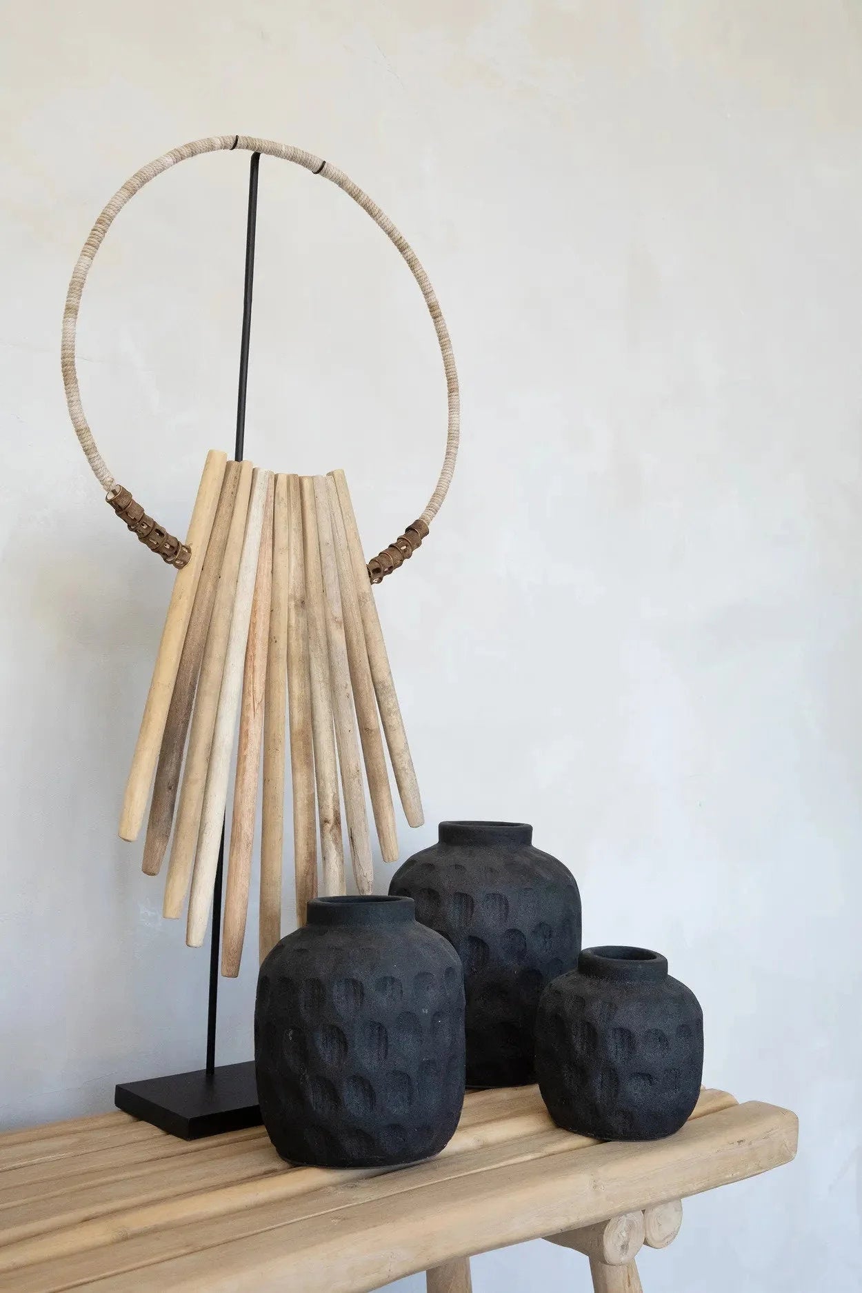 Art tribal décoratif avec trois vases noirs texturés sur socle en bois naturel