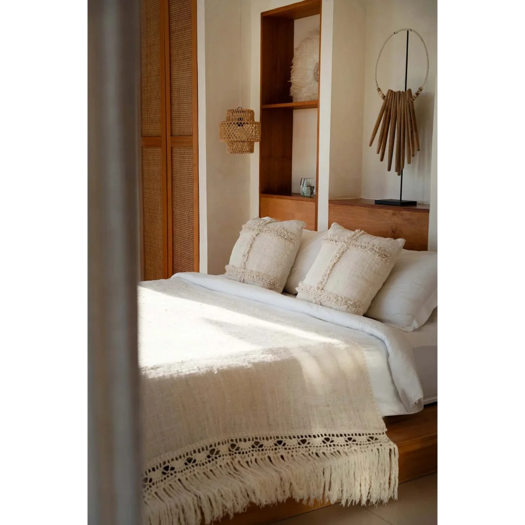 Lit avec linge blanc et coussins décoratifs à franges, idéal pour la décoration intérieure