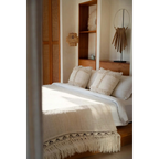 Lit avec linge blanc et coussins décoratifs à franges, idéal pour la décoration intérieure