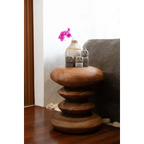 Table d’appoint en bois clair avec vase de fleurs roses et statues en pierre grise