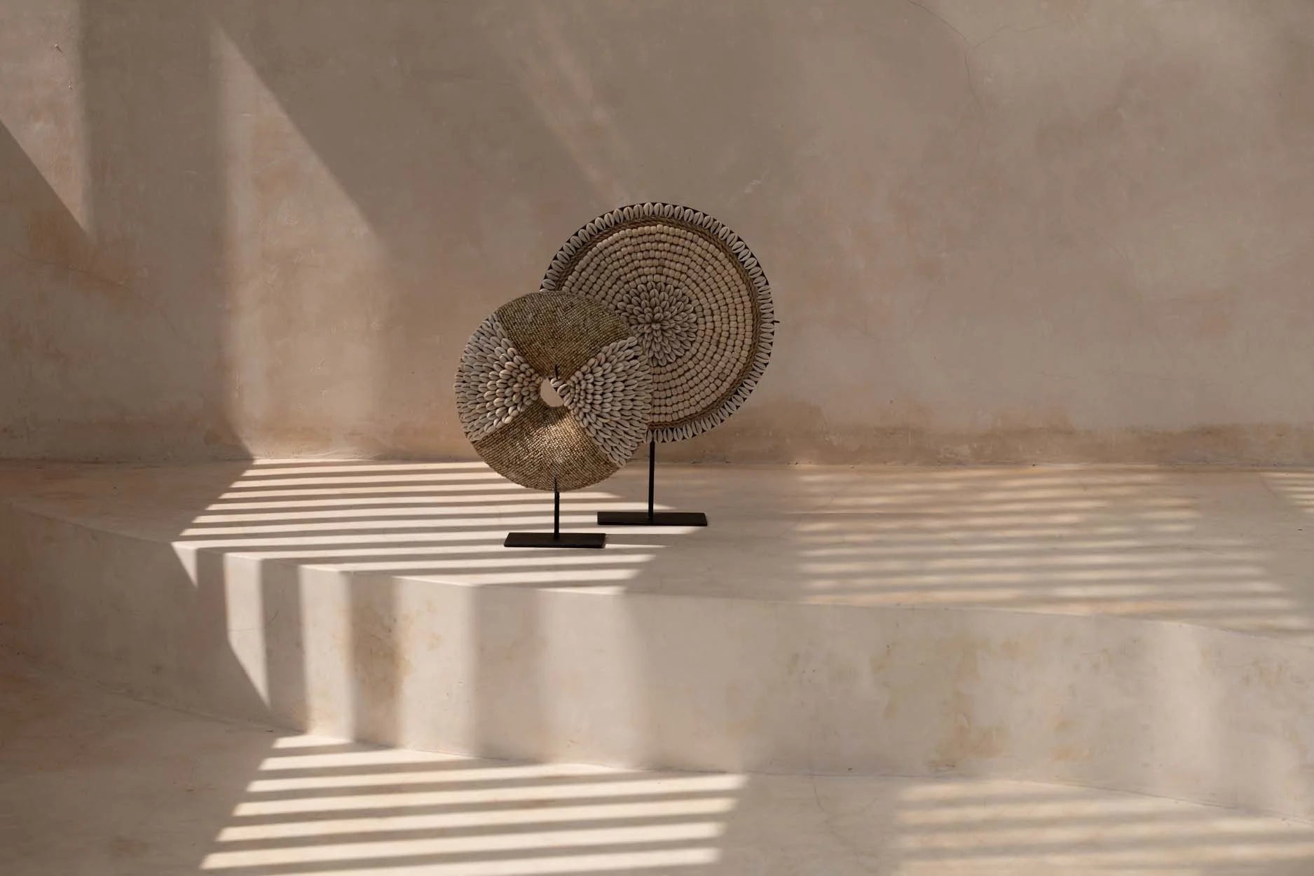 Deux disques décoratifs en fibres naturelles et coquillages sur socle noir