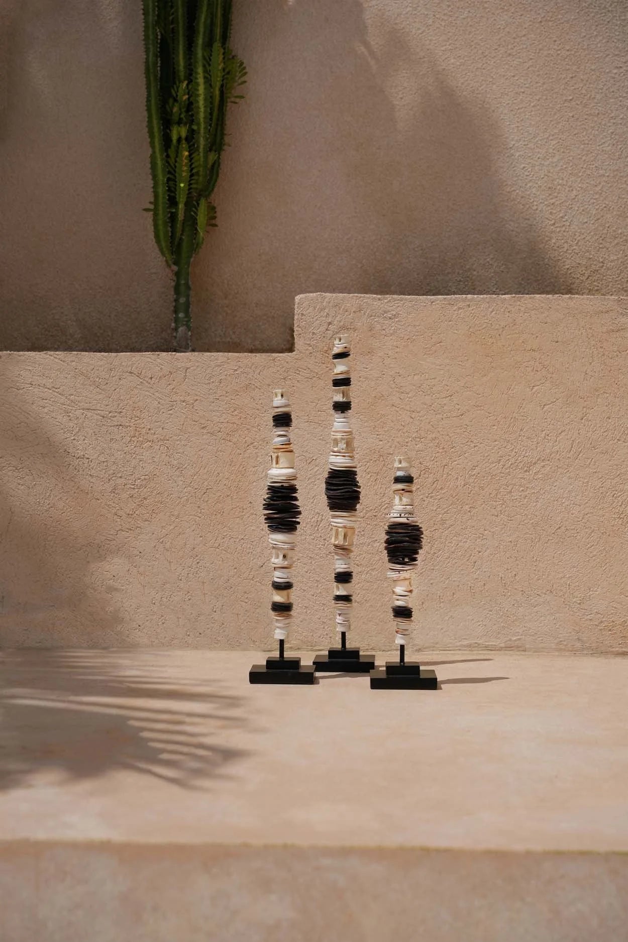 Trois totems sculpturaux en perles noir et blanc empilées sur socles noirs