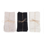 Trois piles de serviettes de table en lin attachées avec de la ficelle.