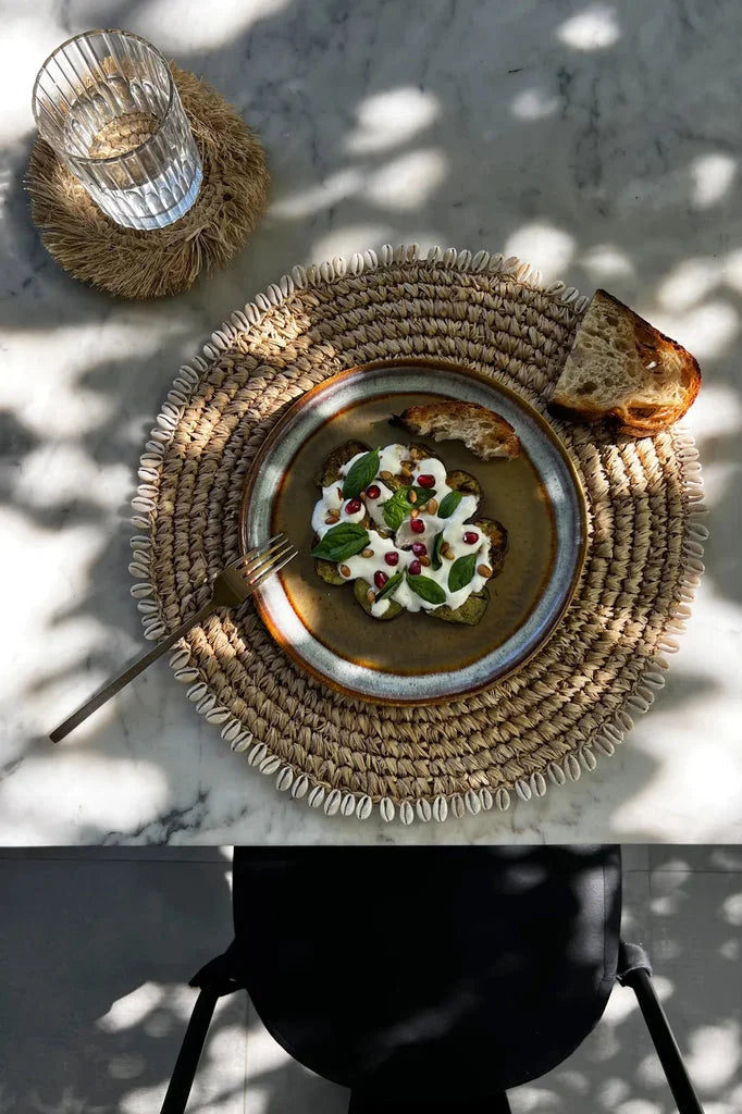 Assiette artisanale de nourriture sur le set de table en coquille de raphia Naturel