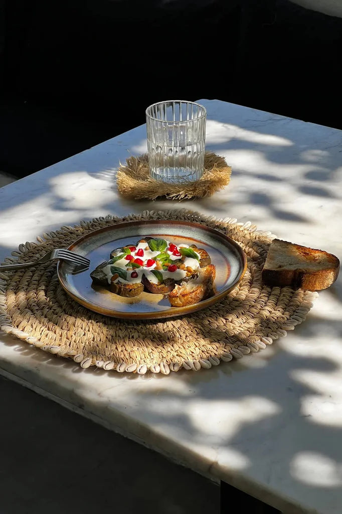 Toast avec crème, verdure et graines de grenade sur le set de table en coquille de raphia naturel